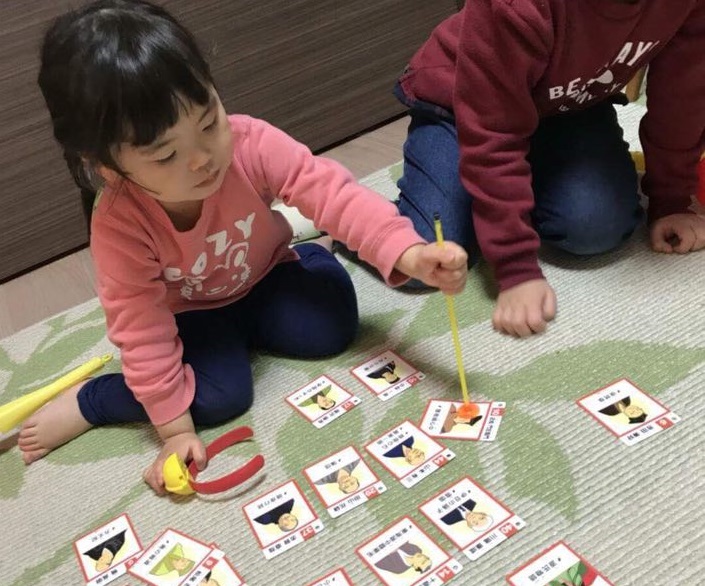 「日本の名作カルタ」で遊ぶ子供ら